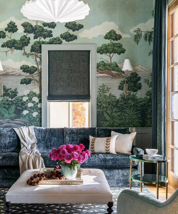 maximalist living room with wall mural, blue velvet sofa, and bright pink flowers on upholstered coffee table