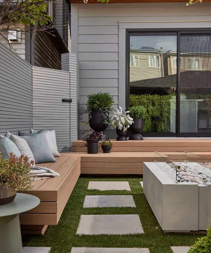 Wooden built-in bench in small backyard space with cushions and contemporary firepit