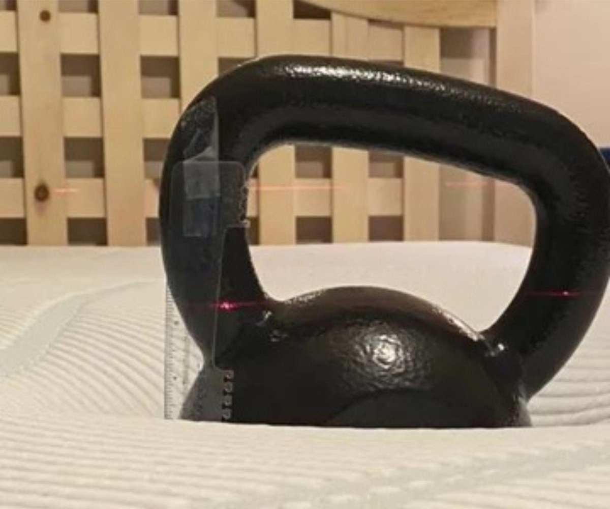 A kettlebell on top of a Tempur-Pedic mattress.