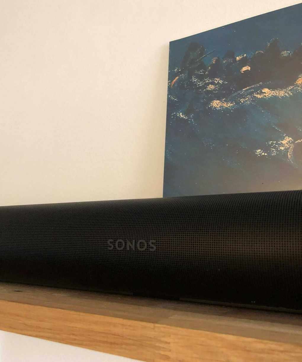 Sonos Arc Ultra soundbar on wooden shelf in front of vinyl sleeve of The Avalanches' Since I Left You and white wall.