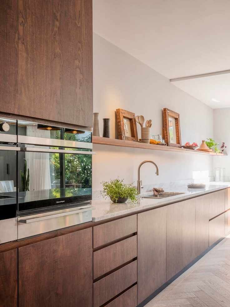 A wooden kitchen with open shelves and marble topped counters