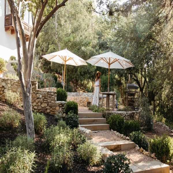 terraced backyard with greenery, white umbrellas and gravel pathways