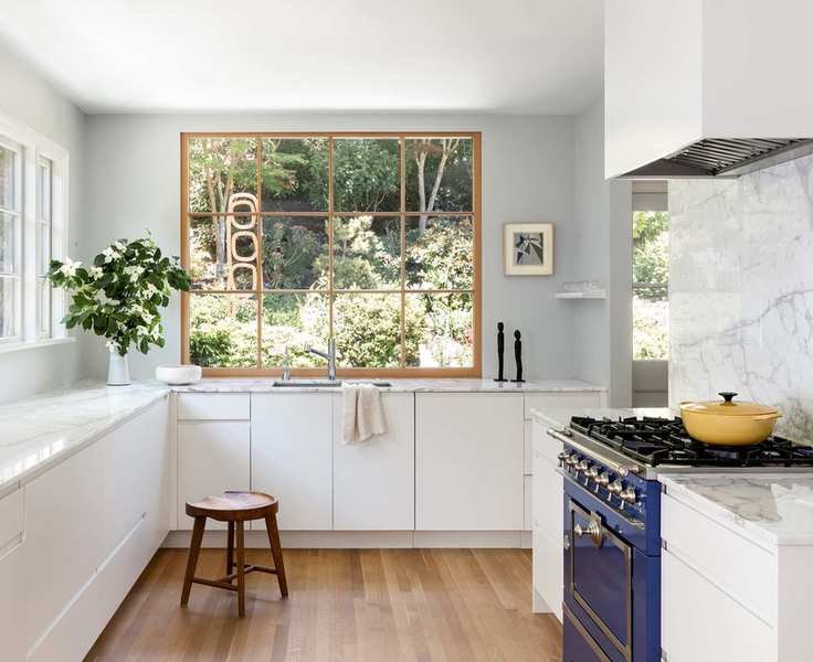 Small white kitchen ideas with white cupboards, a white marble backsplash, blue range and large windows