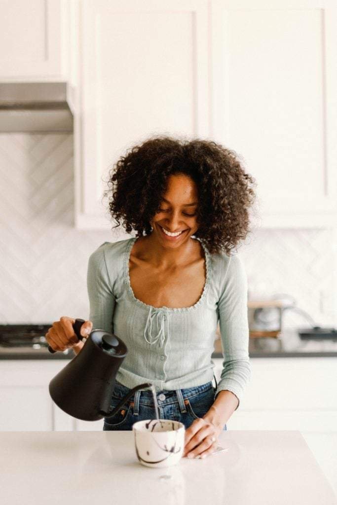 woman pouring tea in kitchen manifestation techniques