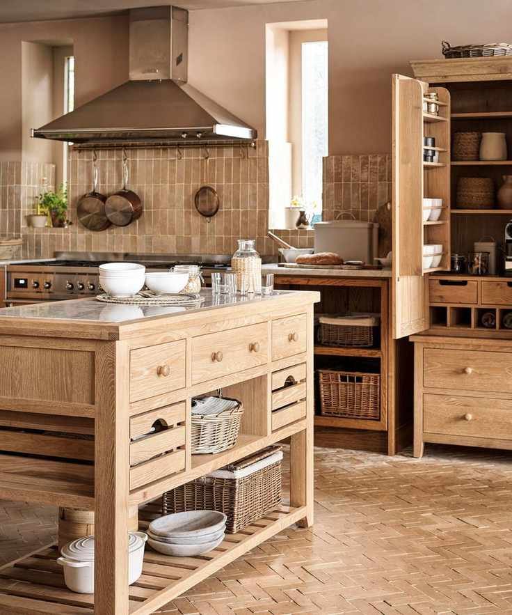 A large solid wood standalone kitchen island in the center of a matching rustic kitchen