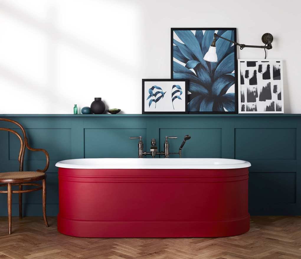 bathroom with white walls, blue painted panels with red painted tub, artwork, herringbone floor