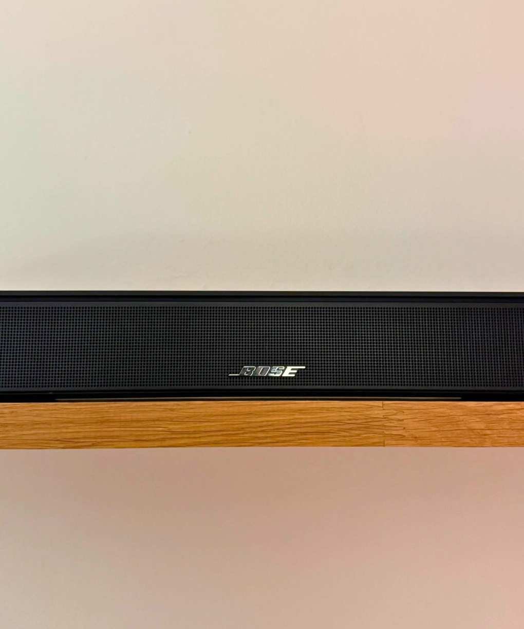 Closeup of the Bose Smart Soundbar on a shelf in front of a white wall.
