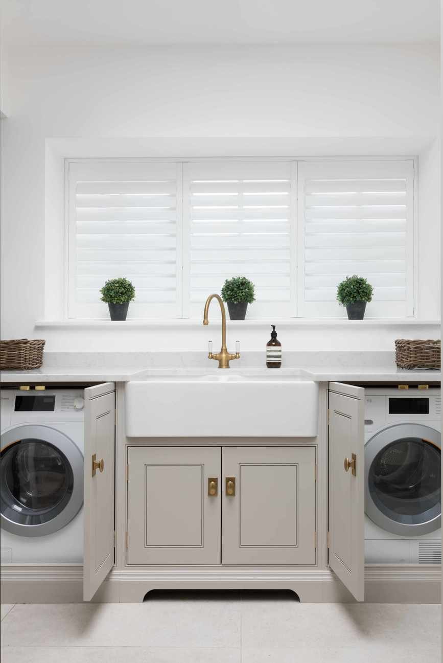 A smart utility room with grey cupboards and brass finishes.