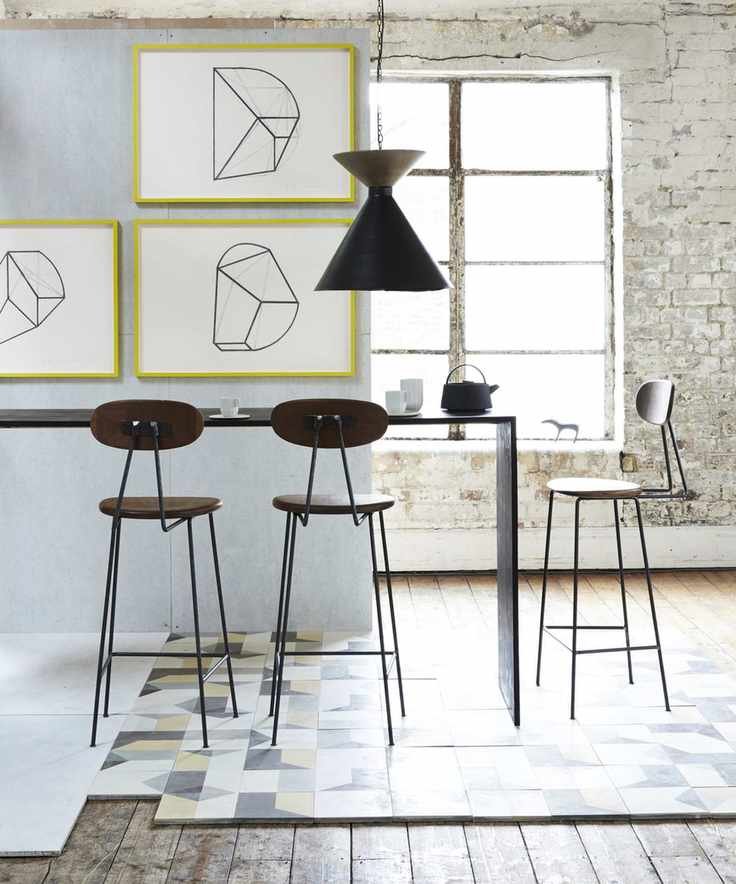 A kitchen with a breakfast bar, zoned with geometric floor tiles amid a natural wood floor