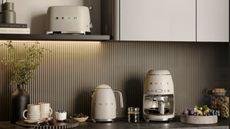 A set of matte cream colored SMEG appliances on a black kitchen counter