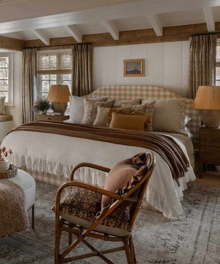 A cottage core bedroom with a bed adorned with pillows and a wooden accent chair