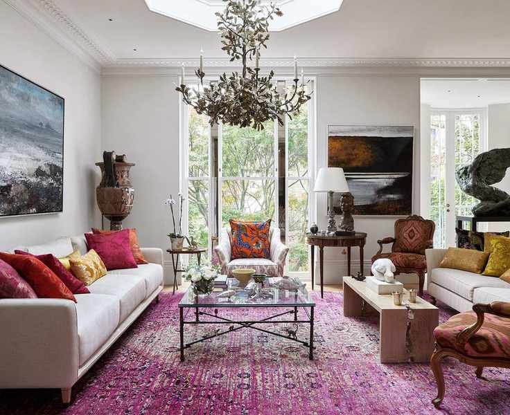 Beige sofas with red and yellow cushions and a large red rug illustrate how to design a living room.