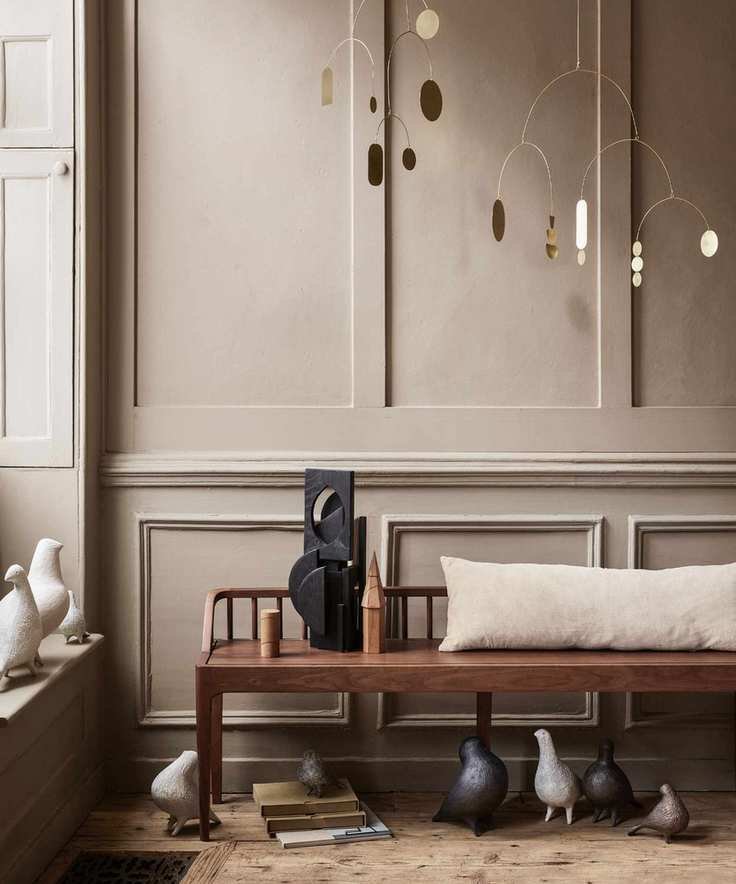 Wooden bench with beige cushion before brown paneling