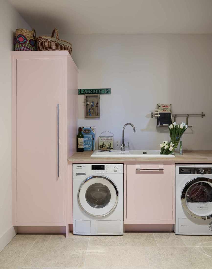 pastel pink laundry room with painted units washing machine and dryer