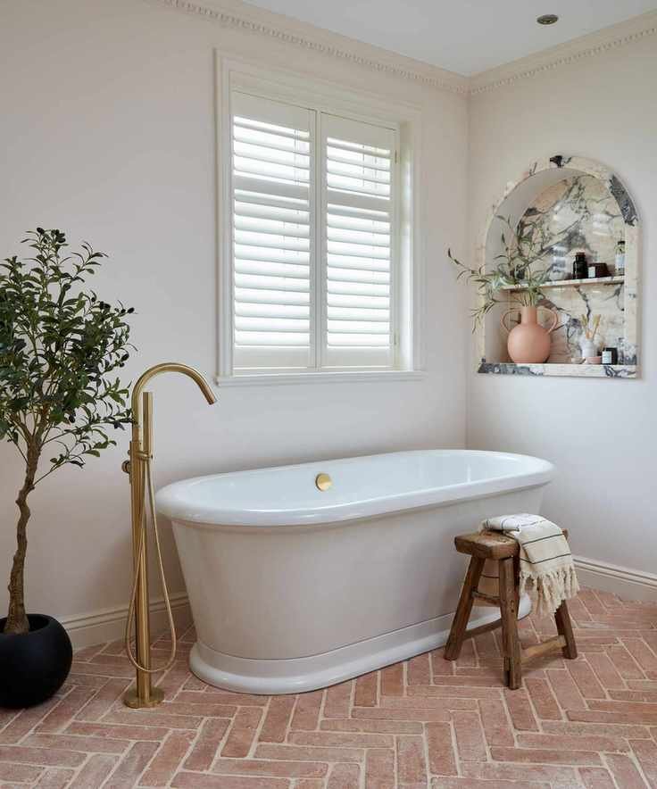 terracotta floor bathroom with marble niche and freestanding bathtub