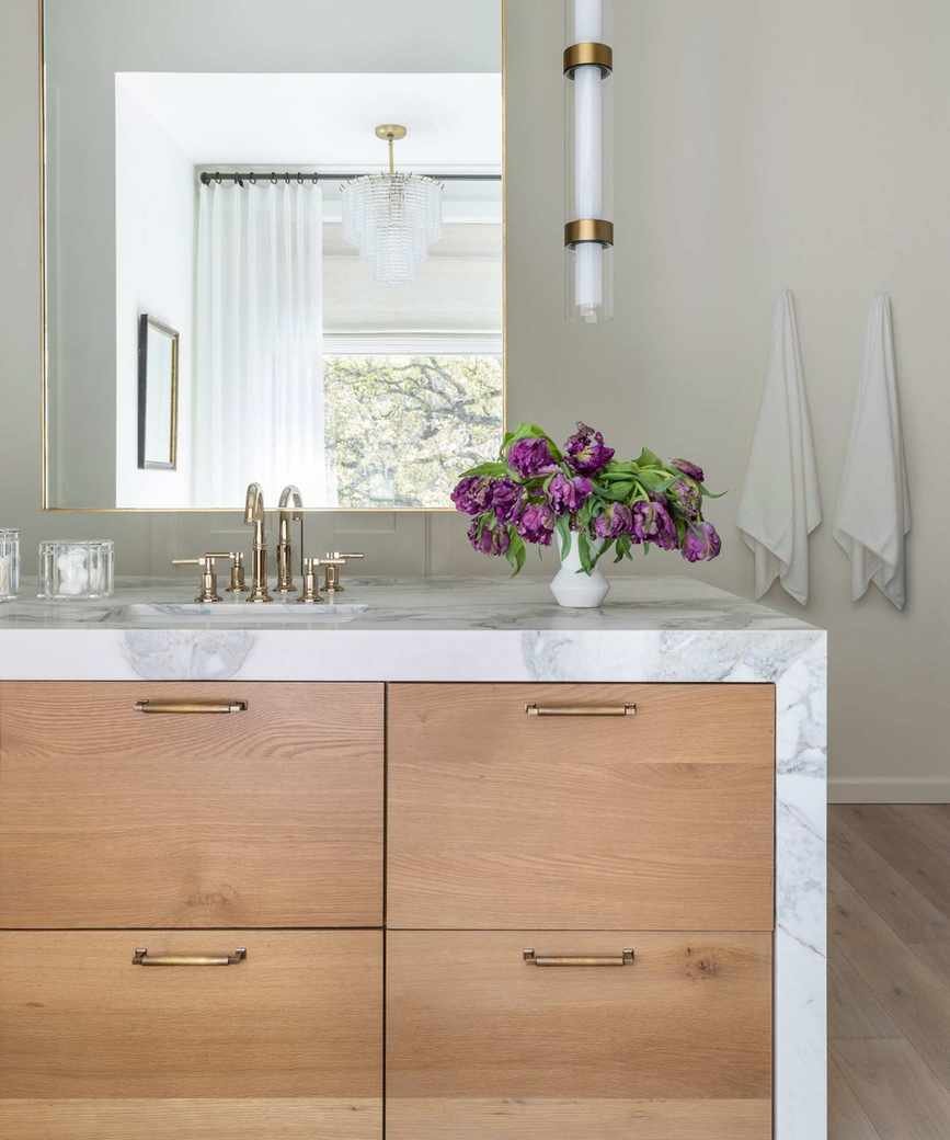 A wood and marble bathroom with a vanity island at the center