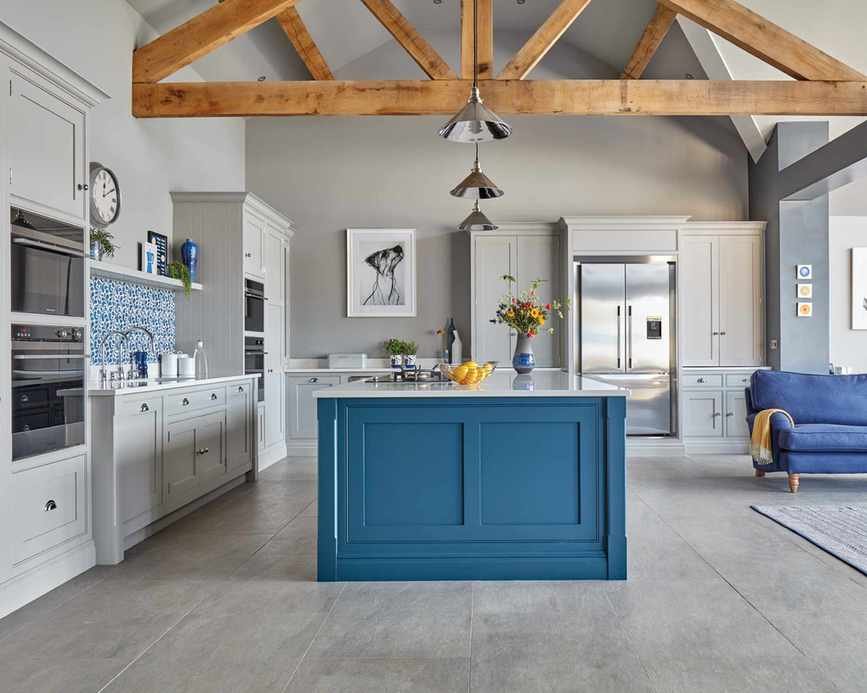 An example of how to paint kitchen cabinets in a large pale gray room with pale gray and bright blue cabinetry.
