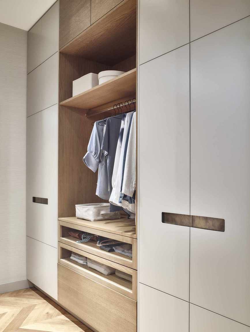 closet with part enclosed and part shelving with some hanging, open shelving and drawers, herringbone floor