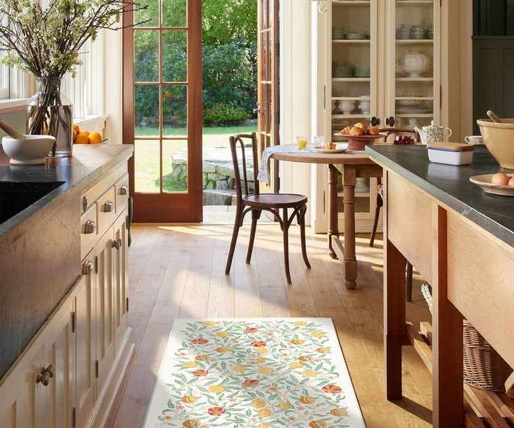 Bright and sunny galley kitchen with white and floral Ruggable runner in between cabinets on left and wooden island on the right